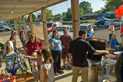 Chris Nordyke serves up hot dogs to a crowd at his State Farm agency's July barbe